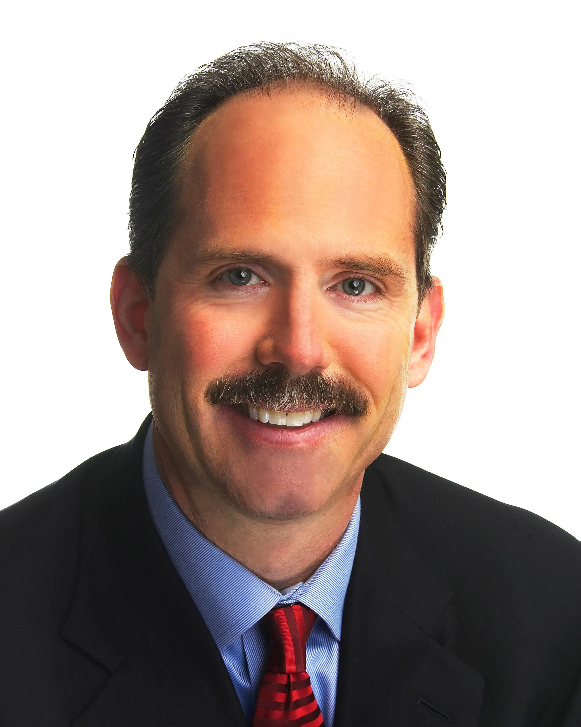 Richard Berry, a moustached man in a dark suit and red tie, in a studio portrait against a white background