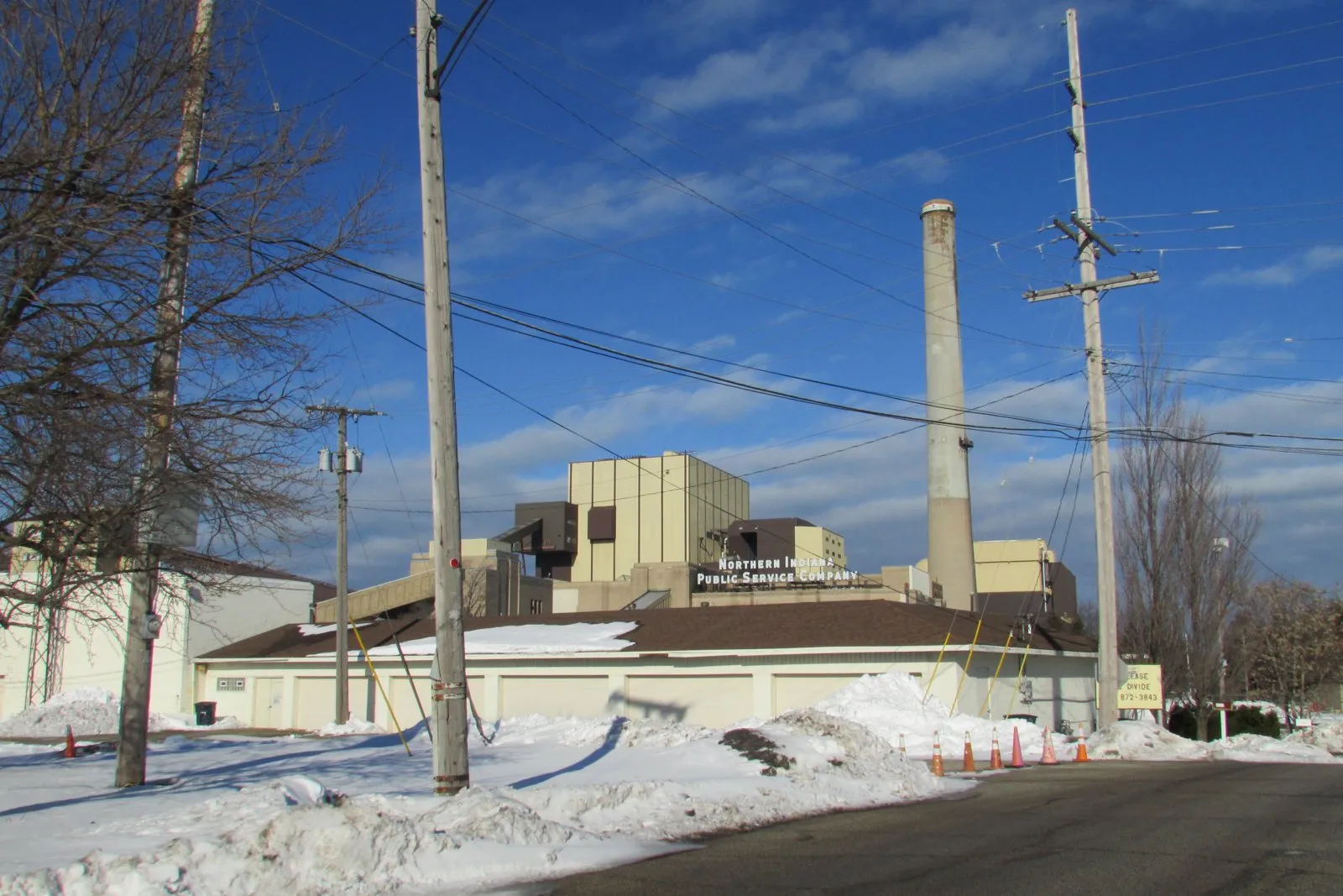 A power plant with a tall smokestack behind a snowy street in Michigan City, Indiana, with the words Northern Indiana Public Service Company on the building